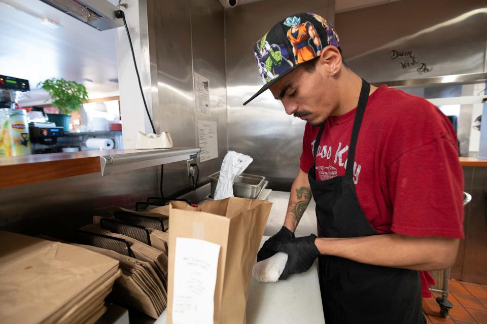 Marcus Gutierrez bags an order at the South Side Pass Key located at 3416 W. Northern Ave. on Wednesday, January 12, 2022.