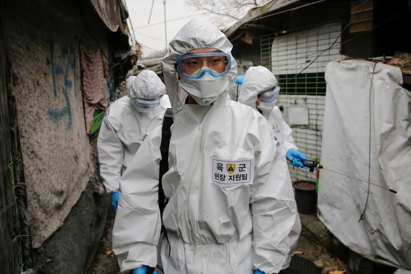 South Korean soldiers in protective gears sanitize shacks at Guryong village in Seoul