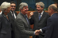 FILE - In this Monday, Jan. 20, 2020 file photo Eurogroup President Mario Centeno, center, shakes hands with German Finance Minister Olaf Scholz, right, next to European Central Bank President Christine Lagarde, left, Cyprus' Economy Minister Constantinos Petrides, second left, and European Commissioner for Economy Paolo Gentiloni, second right, during a meeting of European Union Finance Ministers in Eurogroup format at the Europa building in Brussels. Governments from the 19 countries that use the euro overcame sharp differences to agree Thursday on measures that could provide more than a half-trillion euros ($550 billion) for companies, workers and health systems to cushion the economic impact of the virus outbreak. Mario Centeno, who heads the finance ministers' group from euro countries, called the package of measures agreed upon "totally unprecedented... Tonight Europe has shown it can deliver when the will is there." (AP Photo/Francisco Seco, File)