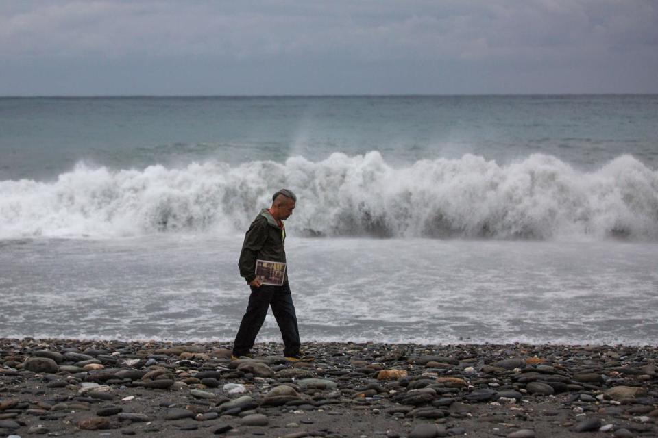 陳進山帶著亡妻照片四處旅行，台東冬日海邊寒冷洶湧，無人戲水玩耍，只有他踽踽獨行。