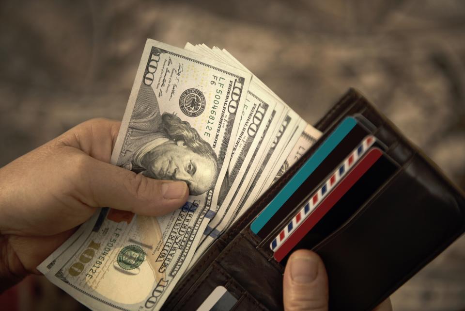 High angle view of unrecognizable mature man placing USA Dollar bills into wallet. Horizontal composition. Image taken with Nikon D800 and developed from Raw format.