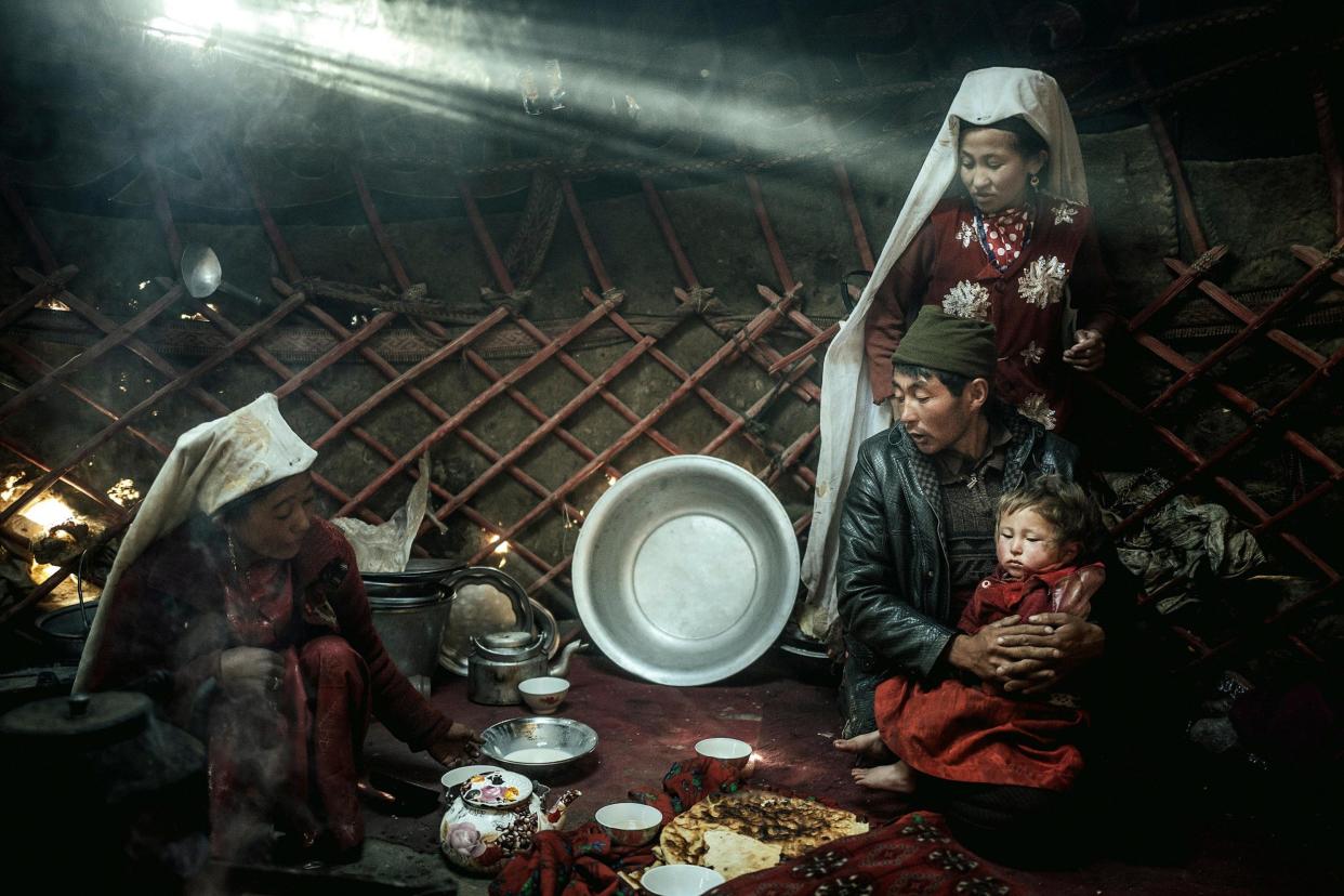 Two woman, a man and a child, morning meal, yurt, a ray of light falls in, nomadic Kyrgyz, Bozai Gumbaz, Wakhan corridor, Badakhshan, Afghanistan