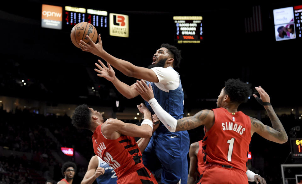 Minnesota Timberwolves center Karl-Anthony Towns, center, collides with Portland Trail Blazers forward Toumani Camara, left, as guard Anfernee Simons, right, defends during the first half of an NBA basketball game in Portland, Ore., Tuesday Feb. 13, 2024. Towns was called for an offensive foul. (AP Photo/Steve Dykes)