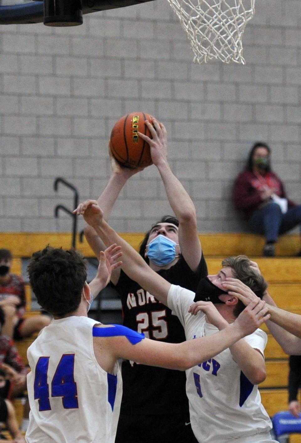 North Quincy's Daithi Quinn shoots over Quincy's Joseph Manton, left, and Coleman Rosa, right, during boys basketball action at Quincy High School, Tuesday, Jan. 19, 2021.