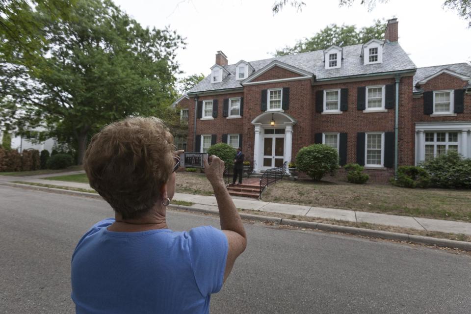 In this photo taken Aug. 12, 2012, Dehlia Jackson of Mechanicsville, Va., photographs Republican Vice Presidential candidate, Rep. Paul Ryan's home in the Courthouse Hill neighborhood in Janesville, Wis. Jackson along with her husband ware driving to Minneapolis and turned off the highway to see Ryan's home. A defining moment for Paul Ryan's hometown came at the height of the Great Recession: General Motors, after nearly a century of making Chevrolets on the banks of the Rock River, shut down its oldest assembly plant and erased 6,000 jobs. A defining question for the campaign Paul Ryan joined this week as the Republican Party's vice presidential nominee just might be what comes next for places like Janesville. (AP Photo/Andy Manis)