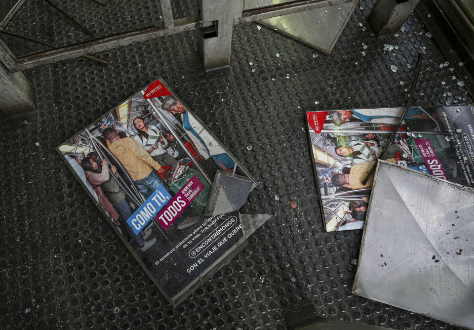 Subway advertisement lays on the floor at a subway station, destroy during last night's protests in Santiago, Chile, Saturday, Oct. 19, 2019. The protests started on Friday afternoon when high school students flooded subway stations, jumping turnstiles, dodging fares and vandalizing stations as part of protests against a fare hike, but by nightfall had extended throughout Santiago with students setting up barricades and fires at the entrances to subway stations. (AP Photo/Esteban Felix)