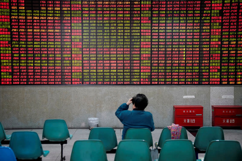 FILE PHOTO: An investor looks at an electronic board showing stock information at a brokerage house in Shanghai, China November 24, 2017. REUTERS/Aly Song/File Photo