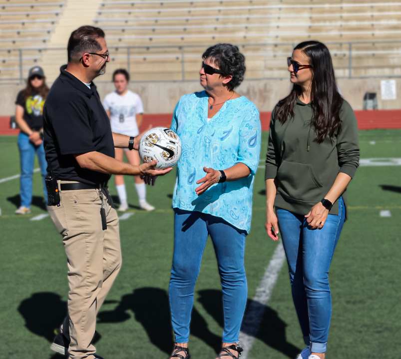 D60 Athletics Director Aaron Bravo, hands a signed soccer ball to the widow of Larry Rogers, Kathleen.