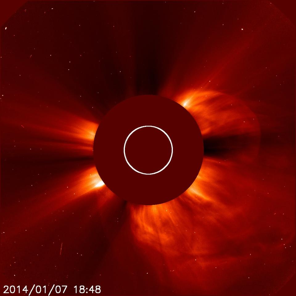 In this Tuesday, Jan. 7, 2014 image made available by NASA, a giant cloud of solar particles, a coronal mass ejection, explodes off the sun, lower right, captured by the European Space Agency and NASA's Solar and Heliospheric Observatory. The sun is obscured to show the atmosphere around it. The solar flare caused the cancellation of a launch to the International Space Station on Wednesday, Jan. 8, 2014. (AP Photo/ESA, NASA - SOHO)