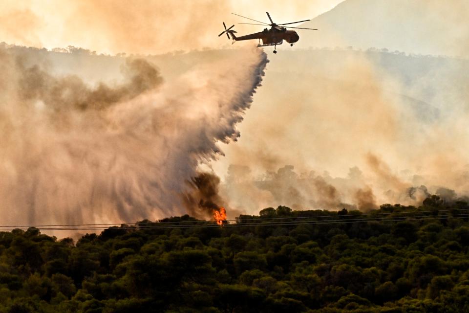 A firefighting aircraft drops water to extinguish a wildfire at Aghios Charalambos area in Loutraki, Corinth, Greece (EPA)