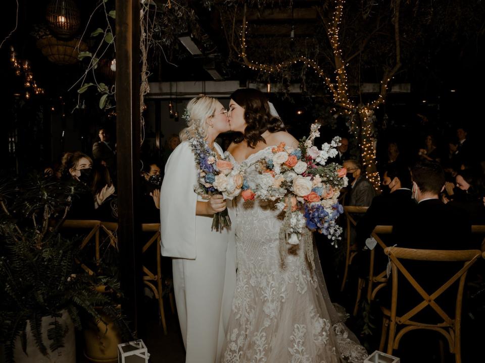 Two brides kiss as they exit their wedding ceremony.