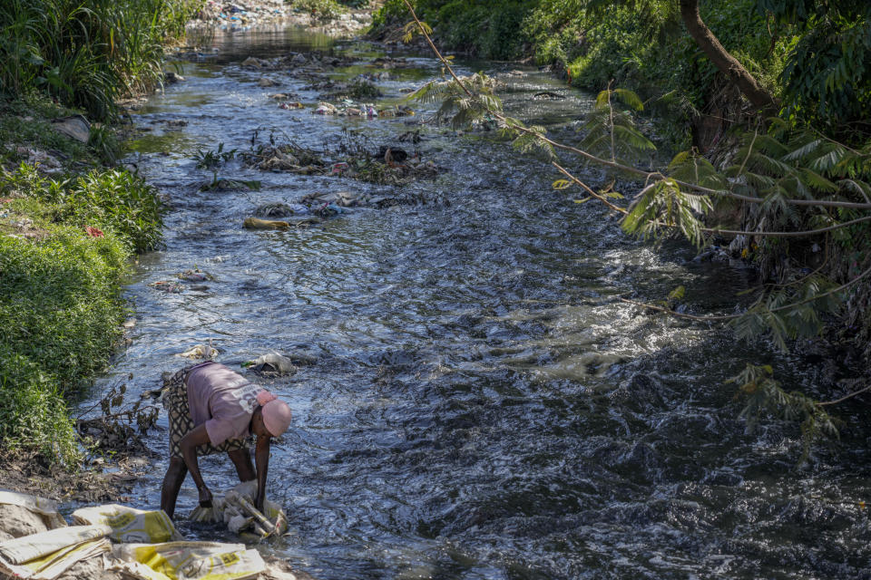 Violet Alunga, 36, washes plastic sacks in the Nairobi river to remove traces of cement for resale to traders who make baskets from them, in the Korogocho area of Nairobi, Kenya, Wednesday, Jan. 11, 2023. As clean water runs short, one of Africa's fastest growing cities is struggling to balance the needs of creating jobs and protecting the environment, and the population of over 4 million feels the strain. (AP Photo/Khalil Senosi)