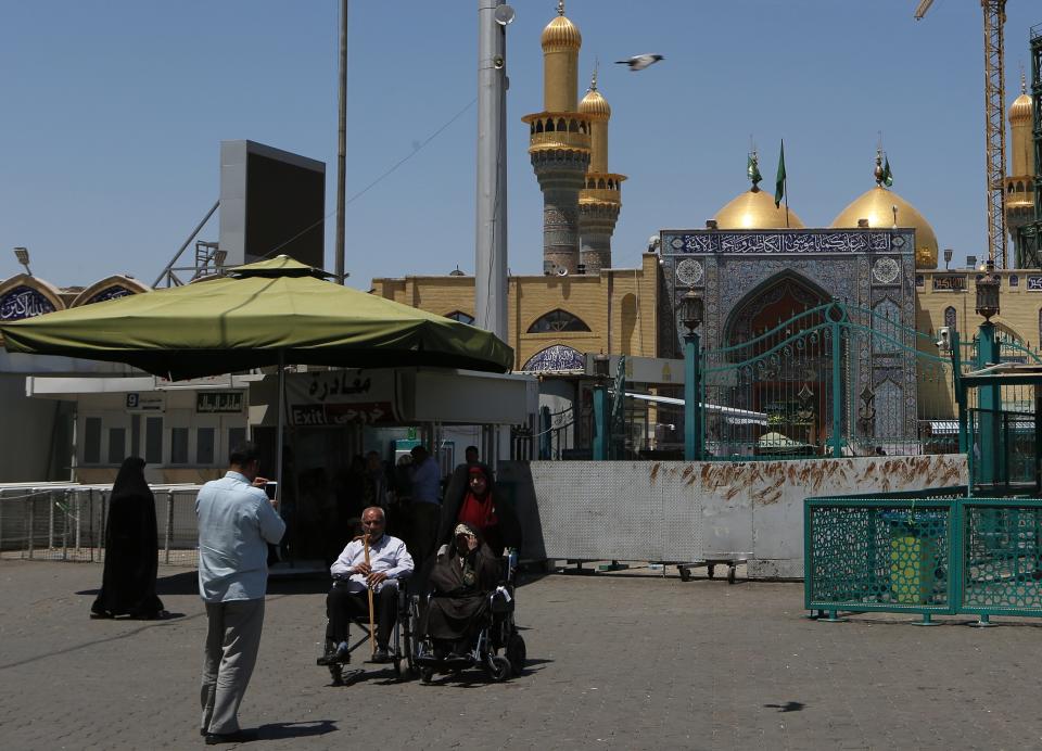 In this Wednesday, May 21, 2019, photo, Shiite pilgrims visit the shrine of Imam Moussa al-Kadhim in Kadhimiya district in north Baghdad, Iraq. Many shop owners in Baghdad's northern Shiite holy neighborhood of Kadhimiya, have seen their sales drop sharply over the past year since U.S. President Donald began reimposing sanctions on Iran, home to the largest number of Shiite Muslims around the world. (AP Photo/Khalid Mohammed)