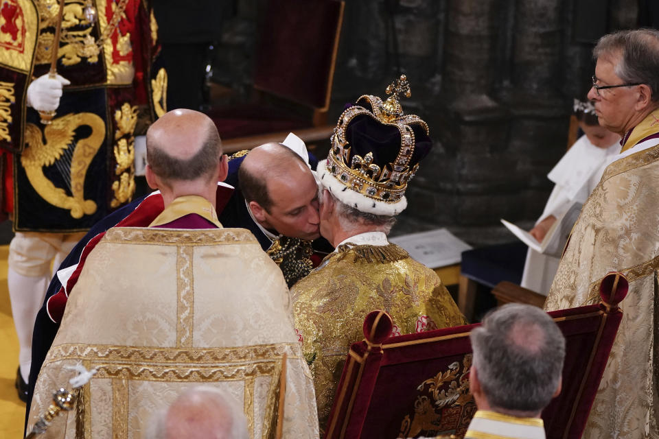 El príncipe Guillermo besa a su padre, el rey Carlos III, durante su ceremonia de coronación en la abadía de Westminster, en Londres el 6 de mayo de 2023. (Yui Mok, Pool vía AP)