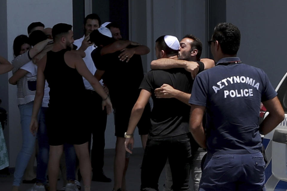 An Israeli teenager is embraced by relatives after being released from Famagusta police headquarters in southeast town of Paralimni, Cyprus, Sunday, July 28, 2019. A lawyer says Cyprus police will release all seven Israeli teenagers who were being detained as suspects in the alleged rape of a 19-year-old British woman. Cypriot Lawyer Yiannis Habaris, who represents two of the seven Israelis, told The Associated Press on Sunday the British woman has been arrested and faces a public nuisance charge. (AP Photo/Petros Karadjias)