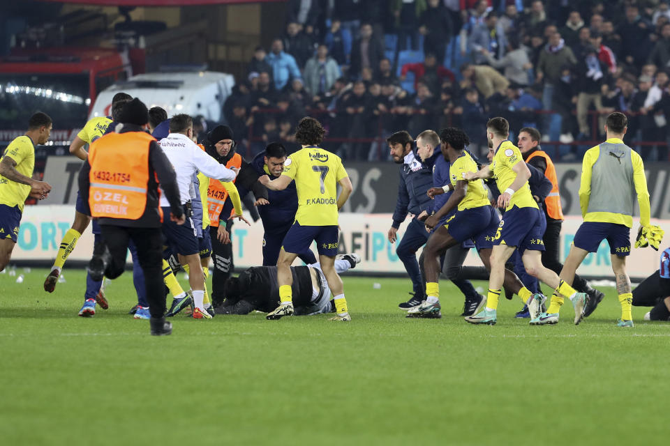 Fenerbahce's players clash with Trabzonspor supporters at the end of Turkish Super Lig soccer match between Trabzonspor and Fenerbahce at the Senol Gunes stadium in Trabzon, Turkey, Sunday, March 17, 2024. Clashes erupted between Trabzonspor fans and Fenerbahce players after local supporters stormed in the pitch at the end of the Turkish Super Lig match. (Huseyin Yavuz/Dia Images via AP)