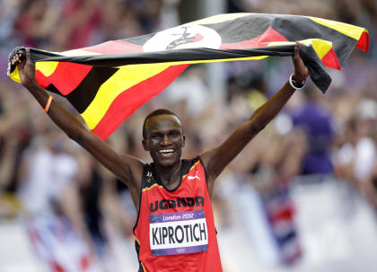 Kiprotich celebrates with his national flag after winning the men's marathon (REUTERS) 