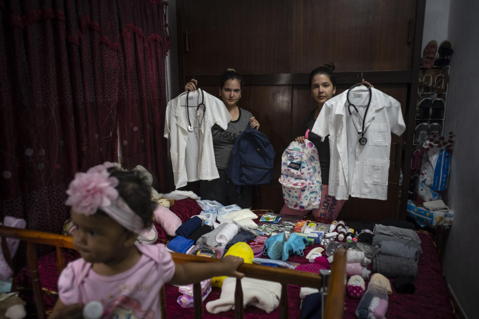 Melanie Rolo González, a la derecha, y su hermana Merlyn, posan para la foto con sus uniformes de estudiantes de medicina mientras empacan provisiones y medicinas para su travesía hacia Estados Unidos, en su casa en La Habana, Cuba, el 10 de diciembre de 2022. El viaje de las dos hermanas es el mismo que han atravesado cientos de miles de cubanos en los últimos dos años con una ola de migración histórica. (AP Foto/Ramon Espinosa)