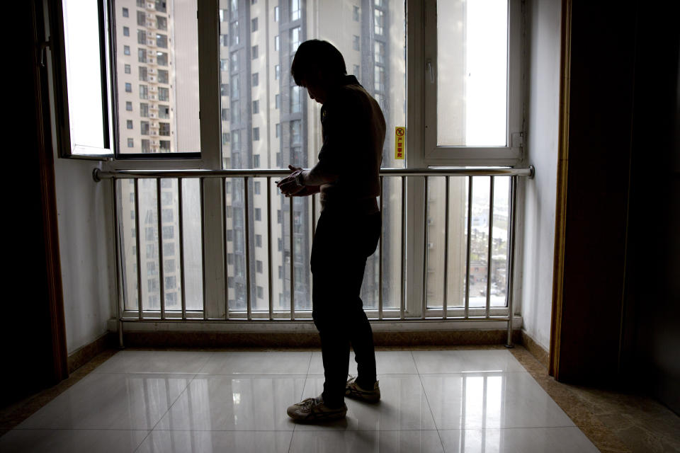 In this March 28, 2019, photo, Yin Hao, who also goes by Yin Qiang, checks his phone while standing in an elevator lobby in Xi'an, northwestern China's Shaanxi Province. Officially, pain pill abuse is an American problem, not a Chinese one. But people in China have fallen into opioid abuse the same way many Americans did, through a doctor's prescription. And despite China's strict regulations, online trafficking networks, which facilitated the spread of opioids in the U.S., also exist in China. (AP Photo/Mark Schiefelbein)