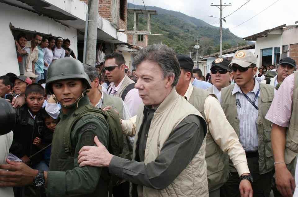 President Juan Manuel Santos holds onto a a police officer upon his arrival to Toribio, southern Colombia, Wednesday, July 11, 2012. Santos visited the town, that was attacked by rebels of the Revolutionary Armed Forces of Colombia, FARC, last week. (AP Photo/Juan Bautista Diaz)
