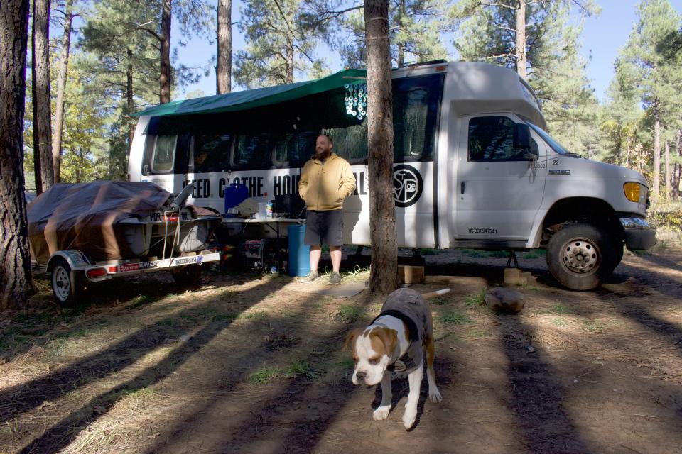 Morgan Rice and his dog, Rio, stand outside of Rice’s van in Coconino National Forest on Oct. 28, 2022. Rice and his girlfriend have called the van home since August.