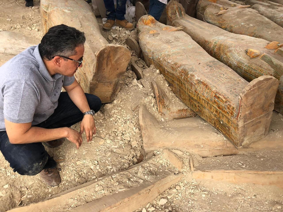 This photo provided by the Egyptian Ministry of Antiquities shows Egyptian Minister of Antiquities Khaled el-Anany looking at recently discovered ancient colored coffins with inscriptions and paintings, in the southern city of Luxor, Egypt, Tuesday, Oct. 15, 2019. The ministry said archeologists found at least 20 wooden coffins in the Asasif Necropolis, describing it as one of the “biggest and most important” discoveries in recent years. (Egyptian Ministry of Antiquities via AP)