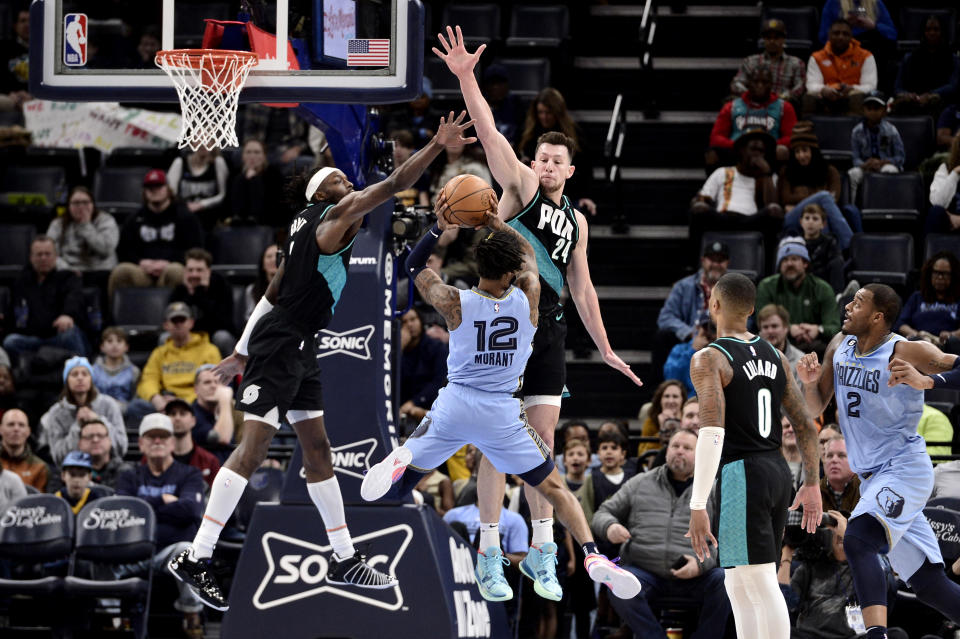 Memphis Grizzlies guard Ja Morant (12) shoots against Portland Trail Blazers forwards Drew Eubanks (24) and Jerami Grant (9) in the first half of an NBA basketball game Wednesday, Feb. 1, 2023, in Memphis, Tenn. (AP Photo/Brandon Dill)