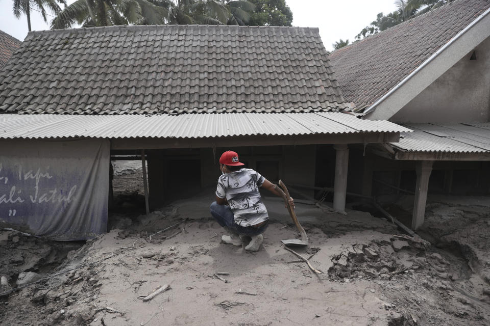 A man inspects his buried house an area hit by the eruption of Mount Semeru in Lumajang district, East Java province, Indonesia, Sunday, Dec. 5, 2021. The death toll from eruption of the highest volcano on Indonesia's most densely populated island of Java has risen with scores still missing, officials said Sunday as rain continued to pound the region and hamper the search.(AP Photo/Trisnadi)