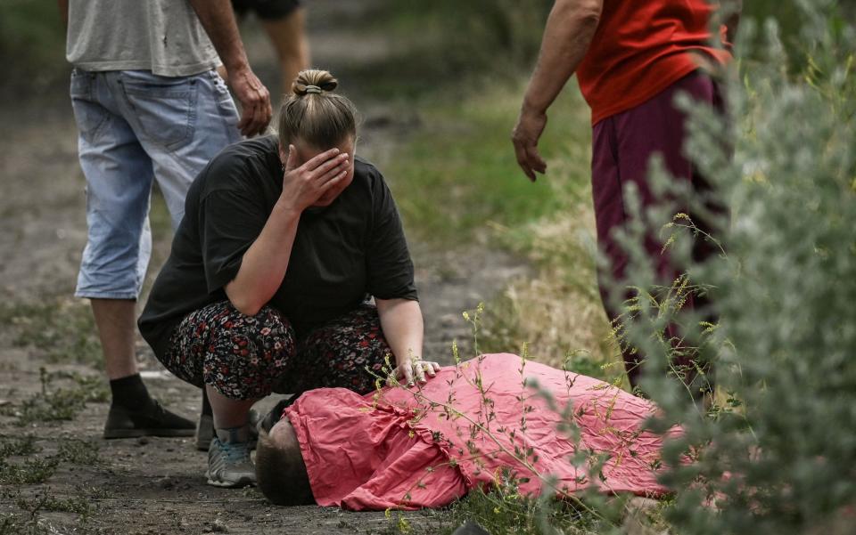 A family mourns the death of a man killed by a cluster rocket in the city of Lysychansk in the eastern Ukrainian region of Donbas - RIS MESSINIS/AFP