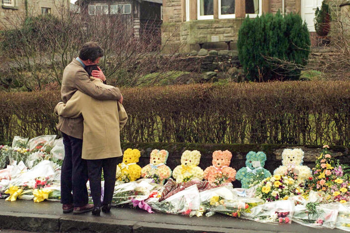 A couple comforts each other as they view floral tributes to mark the death of children in a shooting tragedy in Dunblane, Scotland, on March 17, 1996. (Tim Graham / Sygma/Corbis via Getty Images file)