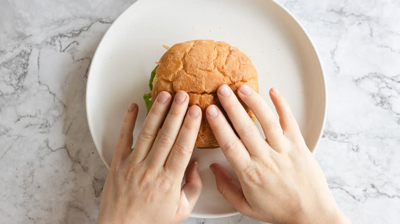 Hands pressing on burger bun