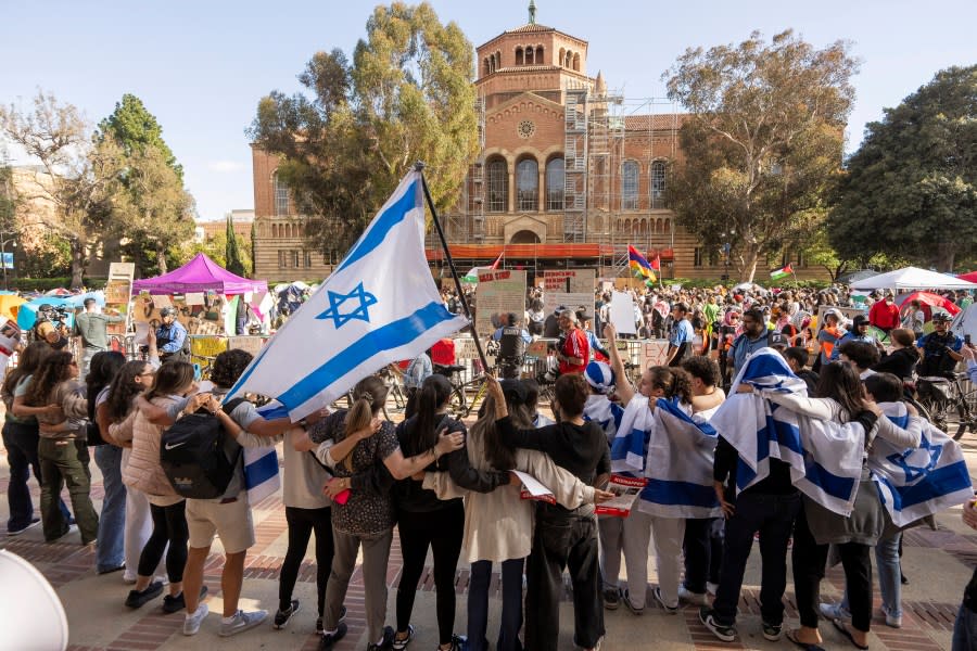 A group of pro-Israel supporters hold arms as they sing and dance outside a pro-Palestinian encampment on the UCLA campus Friday, April 26, 2024, in Los Angeles. As the death toll mounts in the war in Gaza and the humanitarian crisis worsens, protesters at universities across the country are demanding schools cut financial ties to Israel and divest from companies they say are enabling the conflict. (AP Photo/Damian Dovarganes)