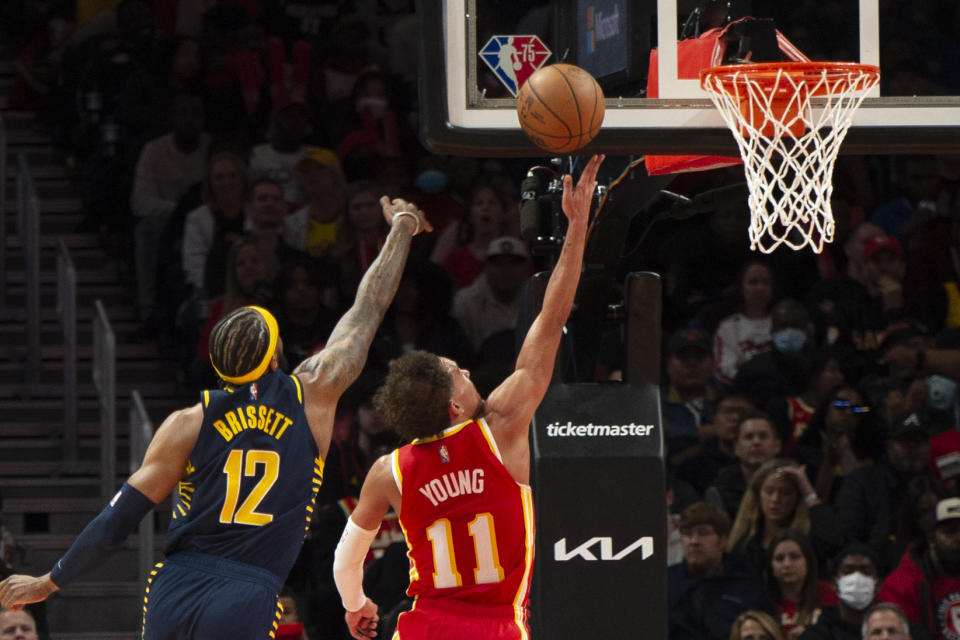 Atlanta Hawks guard Trae Young (11) scores past Indiana Pacers forward Oshae Brissett (12) during the second half of an NBA basketball game Sunday, March 13, 2022, in Atlanta. (AP Photo/Hakim Wright Sr.)