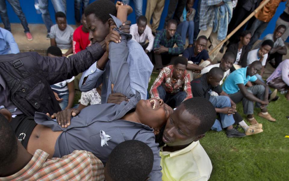 A wailing and distraught Rwandan woman, one of dozens overcome by grief at recalling the horror of the genocide, is carried away to receive help during a public ceremony to mark the 20th anniversary of the Rwandan genocide, at Amahoro stadium in Kigali, Rwanda Monday, April 7, 2014. Sorrowful wails and uncontrollable sobs resounded Monday as thousands of Rwandans packed the country's main sports stadium to mark the 20th anniversary of the beginning of a devastating 100-day genocide. (AP Photo/Ben Curtis)