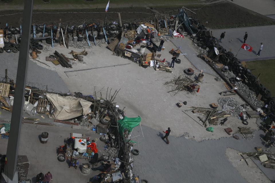 This photo taken throughout a window shows people at barricades at the regional administration building that they had seized earlier in Donetsk, Ukraine, Friday, April 18, 2014. Pro-Russian insurgents in Ukraine’s east who have been occupying government buildings in more than 10 cities said Friday they will only leave them if the interim government in Kiev resigns.(AP Photo/Sergei Grits)