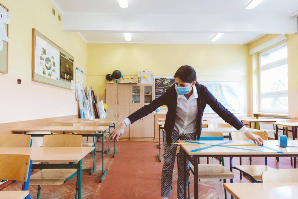 The teacher measuring and marking places in the classroom that are to be empty after students return to school after the coronovirus pandemic. Covid-19