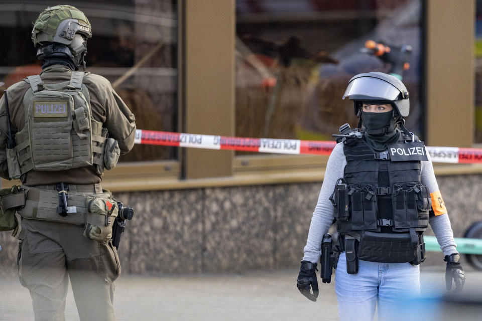 Armed police officers stay in front of a health club in Duisburg, Germany, Tuesday, April 18, 2023. German police say several people have been injured in an attack at a gym in the western city of Duisburg. Tuesday evening’s attack occurred in the old city of Duisburg and police asked residents to avoid the area. (Christoph Reichwein/dpa via AP)