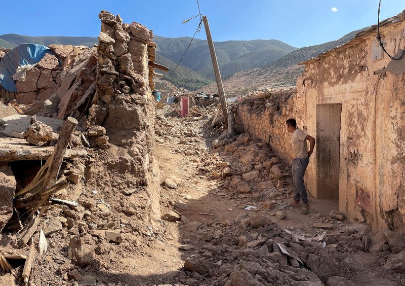 A person stands near damaged houses in Tafeghaghte