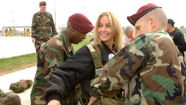 Bo Derek smiling in a black outfit getting suited up