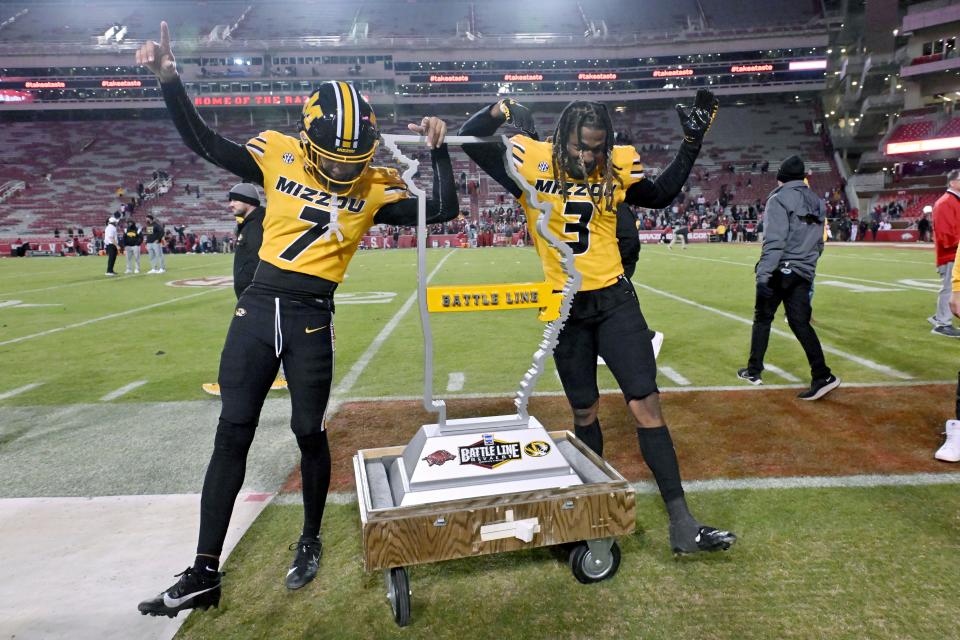 Missouri's Kris Abrams-Draine (7) and Sidney Williams (3) celebrate with the Battle Line trophy after the team's win over Arkansas in an NCAA college football game Friday, Nov. 24, 2023, in Fayetteville, Ark. (AP Photo/Michael Woods)