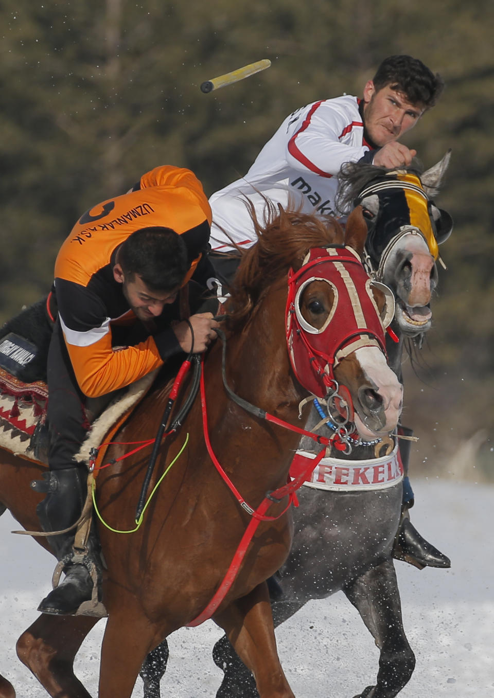 A rider throws the javelin during a game of Cirit, a traditional Turkish equestrian sport that dates back to the martial horsemen who spearheaded the historical conquests of central Asia's Turkic tribes, between the Comrades and the Experts local sporting clubs, in Erzurum, eastern Turkey, Friday, March 5, 2021. The game that was developed more than a 1,000 years ago, revolves around a rider trying to spear his or her opponent with a "javelin" - these days, a rubber-tipped, 100 centimeter (40 inch) length of wood. A rider from each opposing team, which can number up to a dozen players, face each other, alternately acting as the thrower and the rider being chased. Cirit was popular within the Ottoman empire, before it was banned as in the early 19th century. However, its popularity returned as is now one of many traditional sports encouraged by the government and tournaments are often arranged during festivals or to celebrate weddings. (AP Photo/Kenan Asyali)