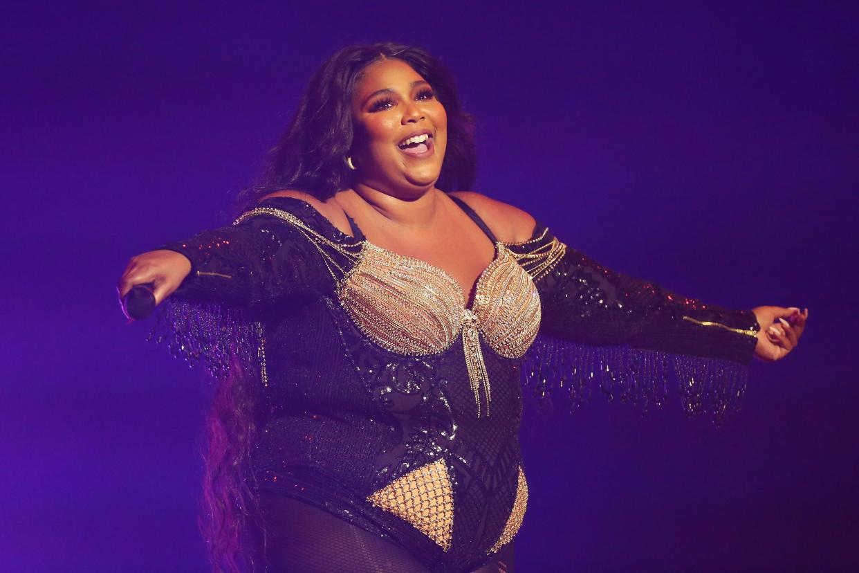 Lizzo poses on stage with her arms out stretched 