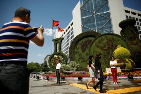 A man takes pictures of a flower display set up ahead of the Belt and Road Forum in central Beijing, China, May 10, 2017. REUTERS/Thomas Peter