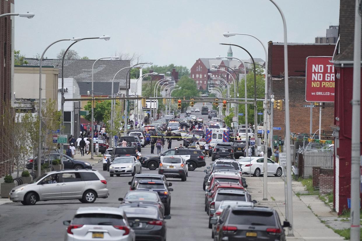 Police vehicles block off the street where at least 10 people were killed in a shooting at a supermarket, Saturday, May 14, 2022 in Buffalo, N.Y.