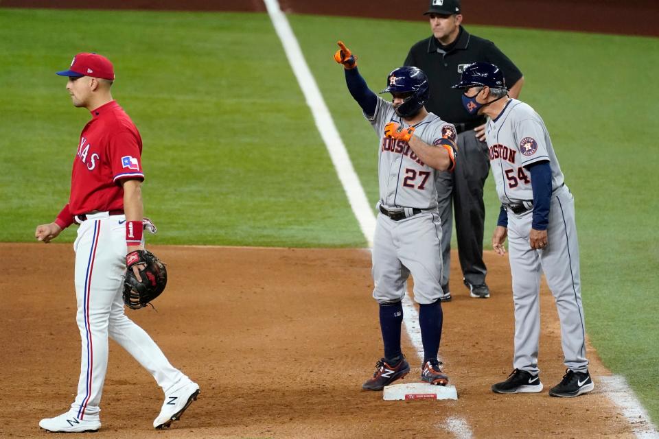 Texas Rangers first baseman Nate Lowe walks away as Houston Astros' Jose Altuve, center and coach Dan Firova (54) celebrate Altuve's RBI single during the eighth inning of a baseball game in Arlington, Texas, Friday, May 21, 2021. Umpire Brian Knight stands at rear. (AP Photo/Tony Gutierrez)