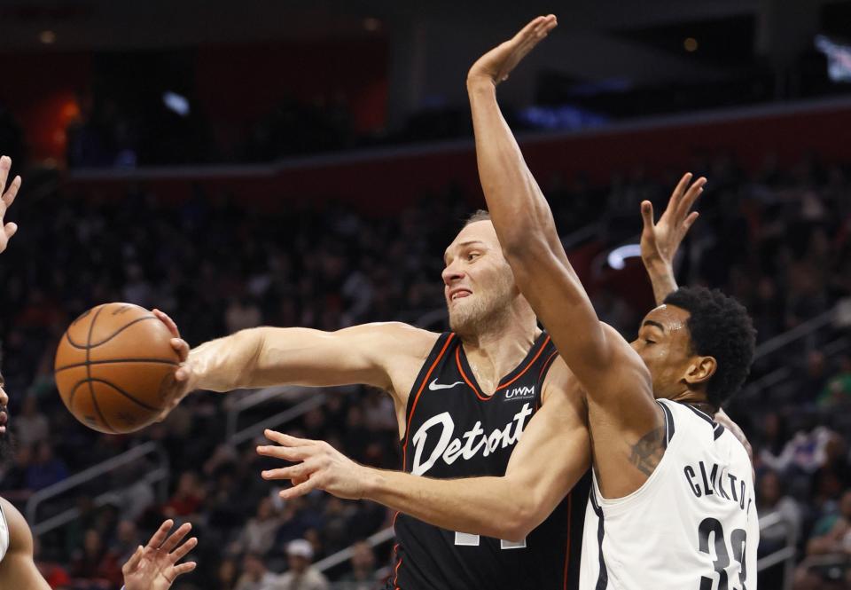Detroit Pistons forward Bojan Bogdanovic (44) passes the ball while being defended by Brooklyn Nets center Nic Claxton (33) during the first half of an NBA basketball game Tuesday, Dec. 26, 2023, in Detroit. (AP Photo/Duane Burleson)