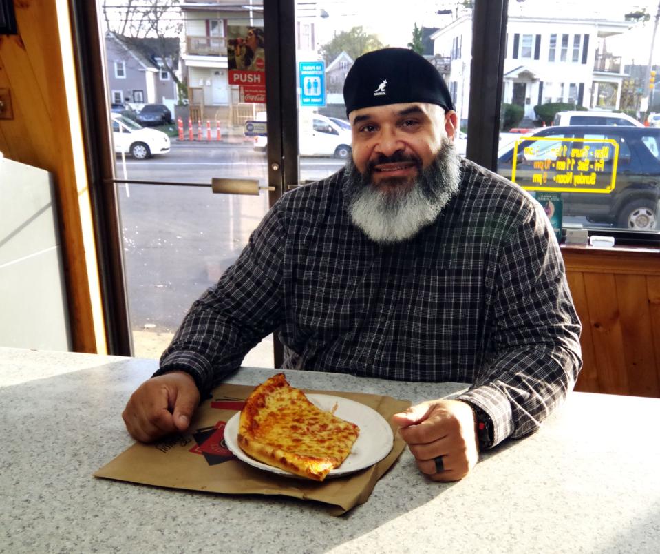 Noel Sierra of Providence who grew up in Brockton, prepares to enjoy a couple of slices of pizza on his way home on Tuesday, Nov. 14, 2023. Sierra's parents still live in Brockton, and while visiting them, stopping by the Supreme House of Pizza for some slices is part of strict ritual he maintains. He enjoys coming, says the staff is always friendly, and he considers the restaurant to be a big part of the Brockton neighborhood.