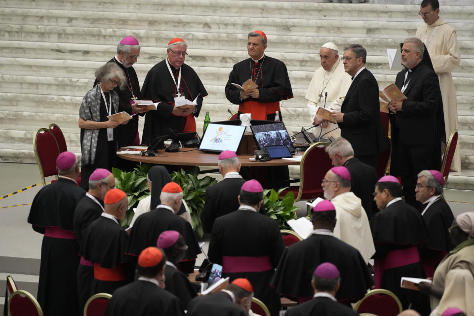 Pope Francis, standing at top fourth from right, participates into the opening session of the 16th General Assembly of the Synod of Bishops in the Paul VI Hall at The Vatican, Wednesday, Oct. 4, 2023. Pope Francis is convening a global gathering of bishops and laypeople to discuss the future of the Catholic Church, including some hot-button issues that have previously been considered off the table for discussion. Key agenda items include women's role in the church, welcoming LGBTQ+ Catholics, and how bishops exercise authority. For the first time, women and laypeople can vote on specific proposals alongside bishops. (AP Photo/Gregorio Borgia)
