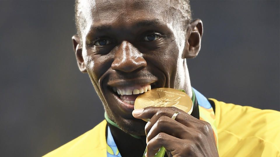 Usain Bolt biting the gold medal after he won the race.