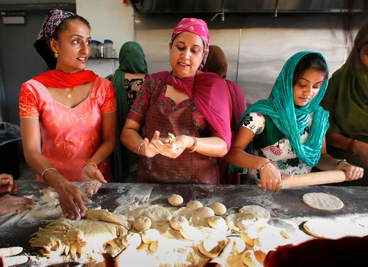 Mandeep Ahuja, left, and Jasbir Dulai, center, make roti at the Sikh Temple of Wisconsin in 2012.